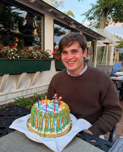Forrest Singletary seated outdoors with a birthday cake at Walloon Lake